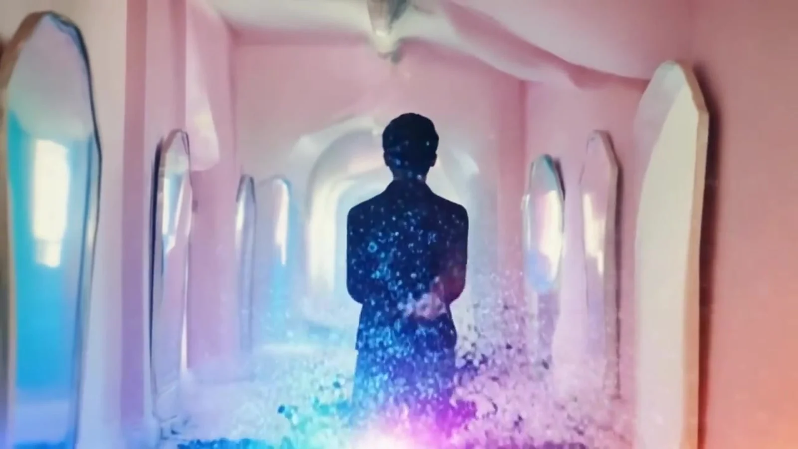 Último plano del videoclip de «Mirror»: una figura de espaldas que se deshace en purpurina azul y rosa en un pasillo rosa de arcos y espejos altos