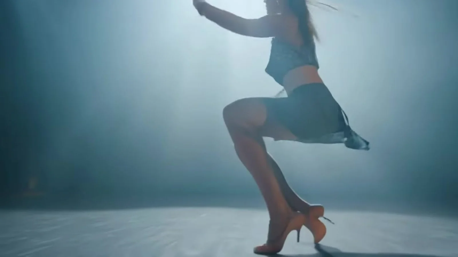 Fotograma del videoclip de «Mood»: las piernas de una bailarina con tacones y falda de vuelo girando sobre un escenario iluminado con luz azul fría