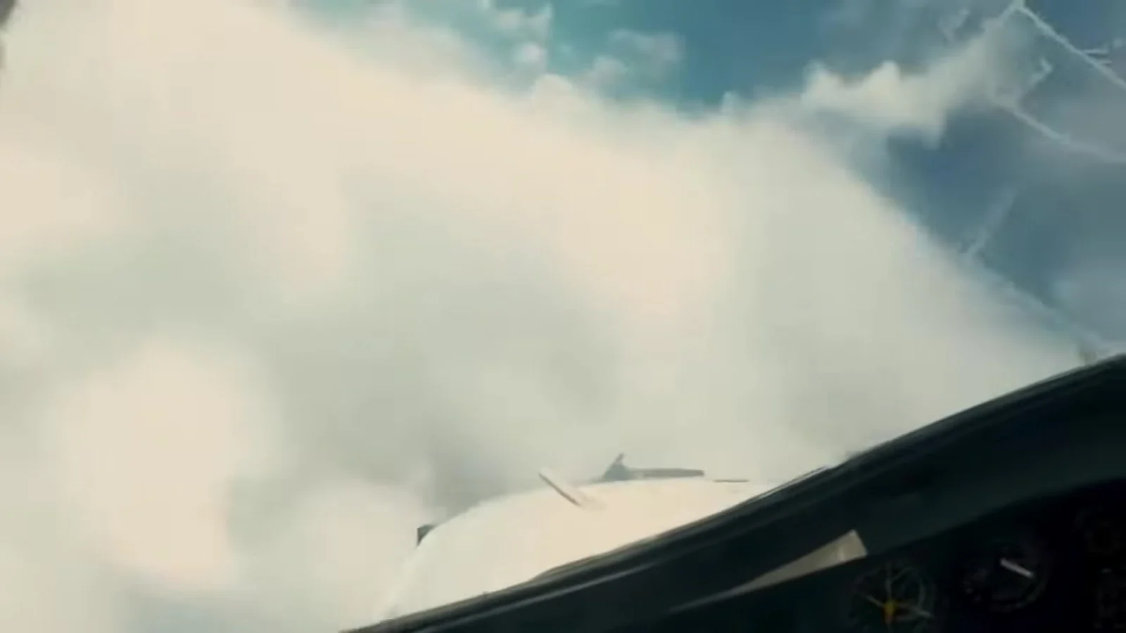 Fotograma del videoclip de «El canario que miente»: una nube blanca pegada al cristal de la cabina de un avión, con el panel de mandos en sombra