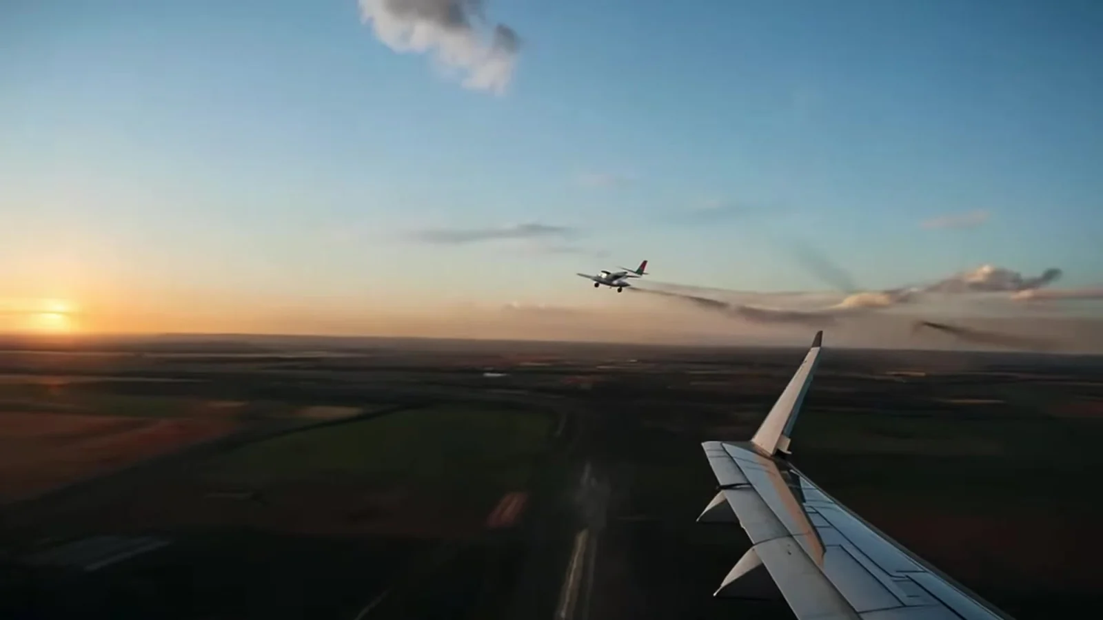 Fotograma del videoclip de «El canario que miente»: el ala blanca de un avión entra en el encuadre sobre una llanura al atardecer, con otro avión pequeño a lo lejos