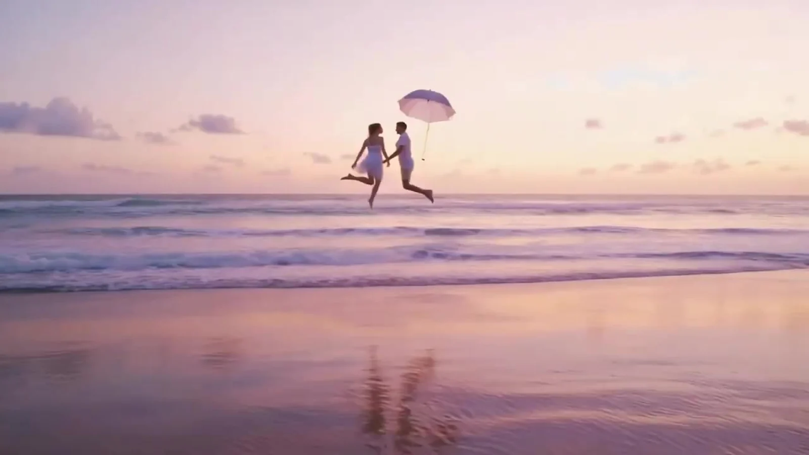 Fotograma del videoclip de «Breeze»: dos figuras pequeñas de la mano flotan sobre la orilla al atardecer con un paraguas blanco y un cielo violeta