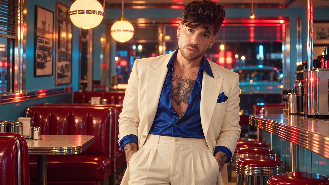 Mike Sain't Louis con traje crema y camisa azul en un diner iluminado con neón (serie 100 fotos retro, n.º 065, en color)