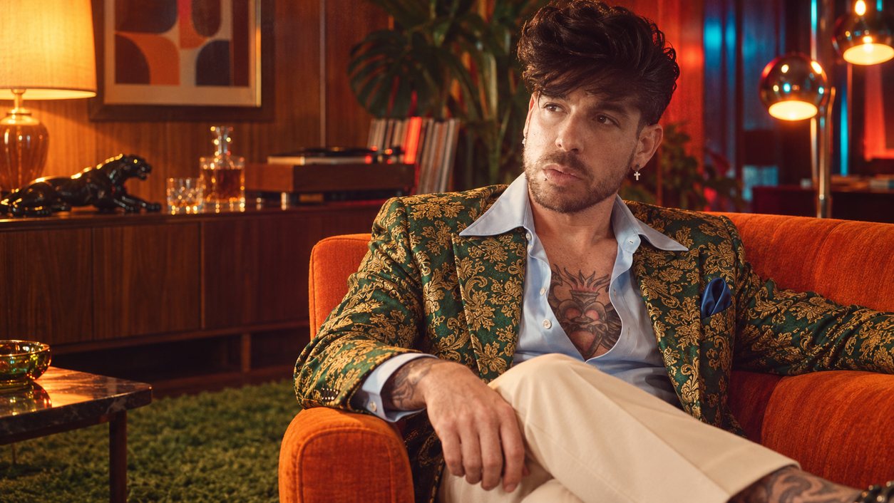 Mike Sain't Louis con chaqueta de brocado verde sentado en un sillón naranja de un salón de madera (serie 100 fotos retro, n.º 073, en color)