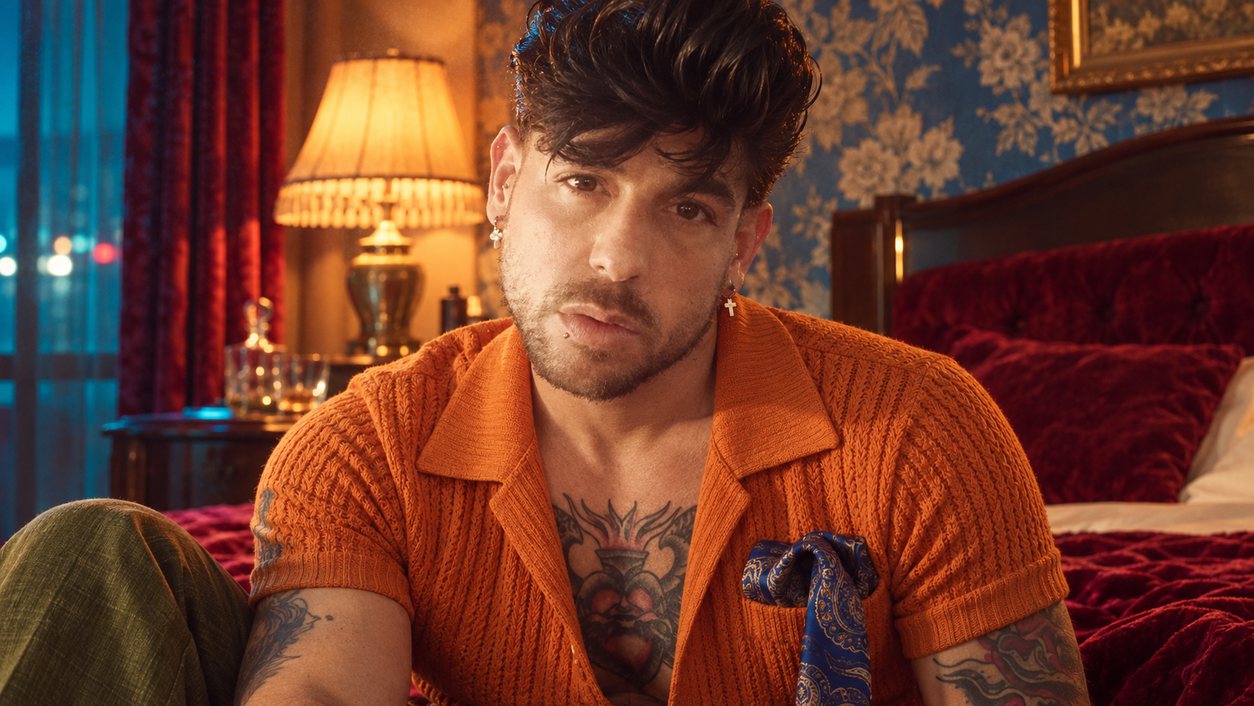 Mike Sain't Louis con camisa de punto naranja sentado en una habitación de hotel con papel pintado azul (serie 100 fotos retro, n.º 079, en color)